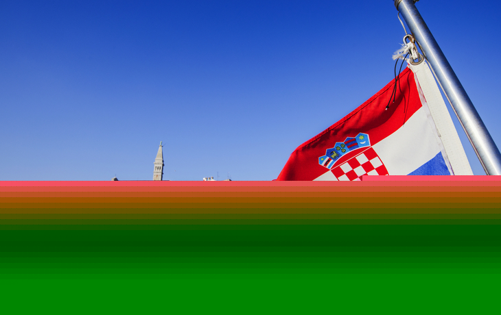 Flagge Kroatiens mit der Stadt Rovinj im Hintergrund